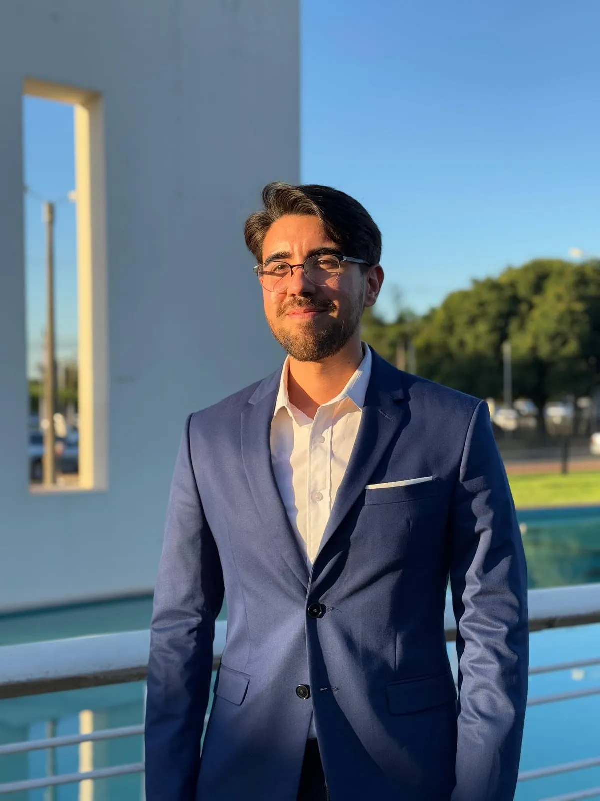 Marthin Meza, de saco azul y camisa blanca, sonriendo al aire libre.